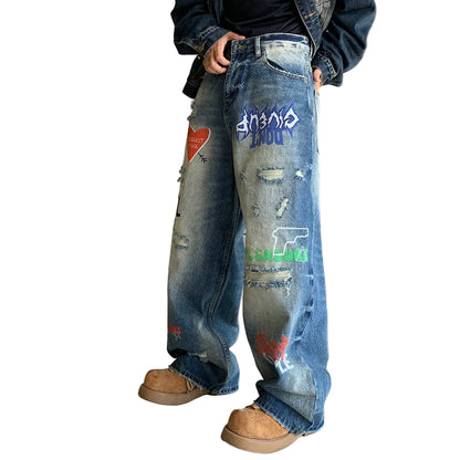 Person wearing distressed blue jeans with graphic designs indoors.